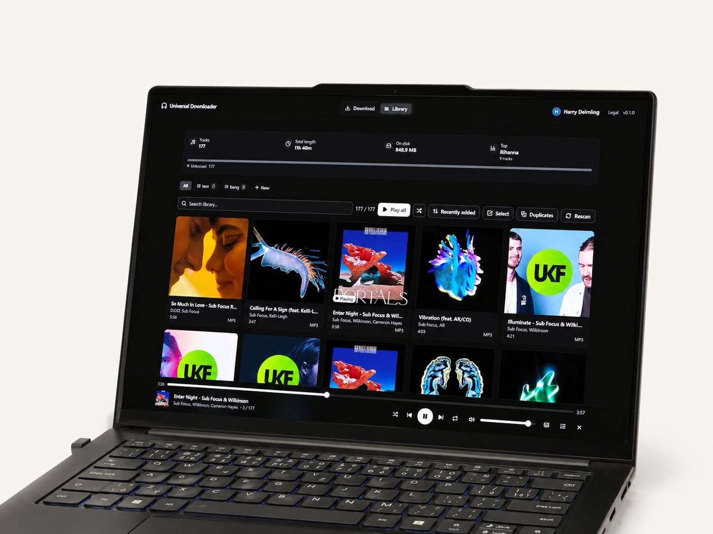 Universal Downloader — library view v dark mode na laptopu, soft directional light